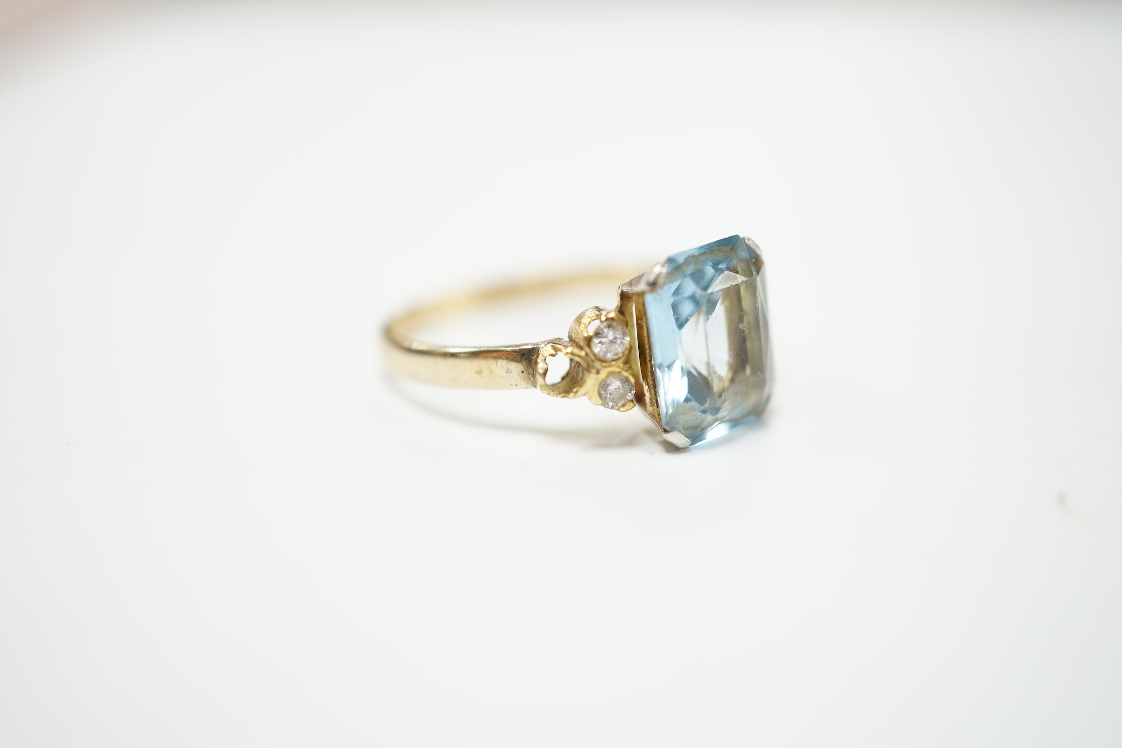 A yellow metal, single stone aquamarine and four stone diamond chip set dress ring, size M, gross weight 2.2 grams.